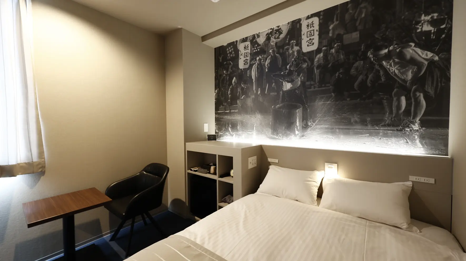 ホテルの部屋、ベッドと壁の壁画がある。